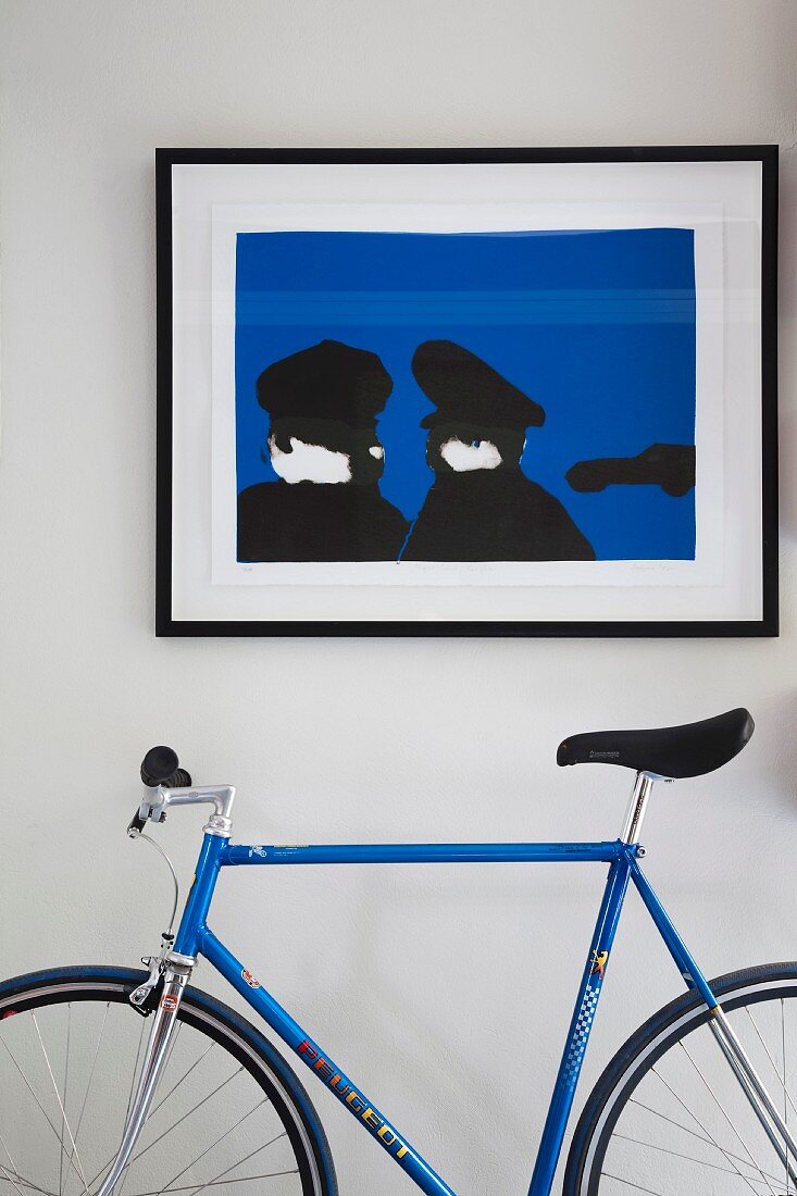 Zeitgenössisches Bild in Blau und Schwarz und farblich passendes Rennrad vor weisser Wand