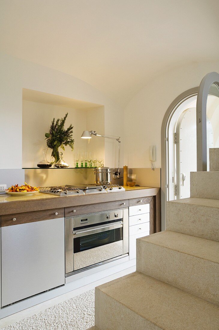 Blick über offene Treppe auf moderne Küchenzeile mit beleuchteter Wandnische