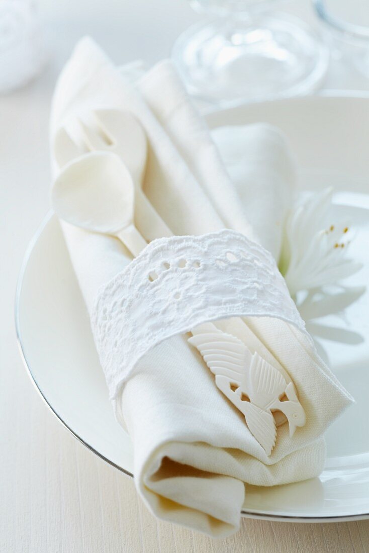 Napkin ring made from lace trim around ornate cutlery & linen napkin on plate
