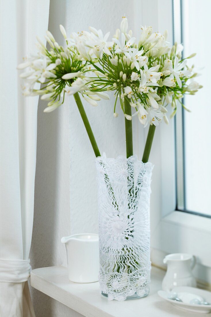 Glass vase wrapped in lace doily on windowsill