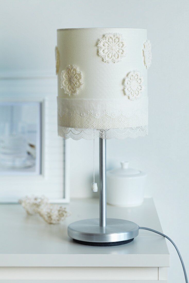 Table lamp lampshade decorated with flower-shaped sections of crocheted doily and gossamer-thin lace trim