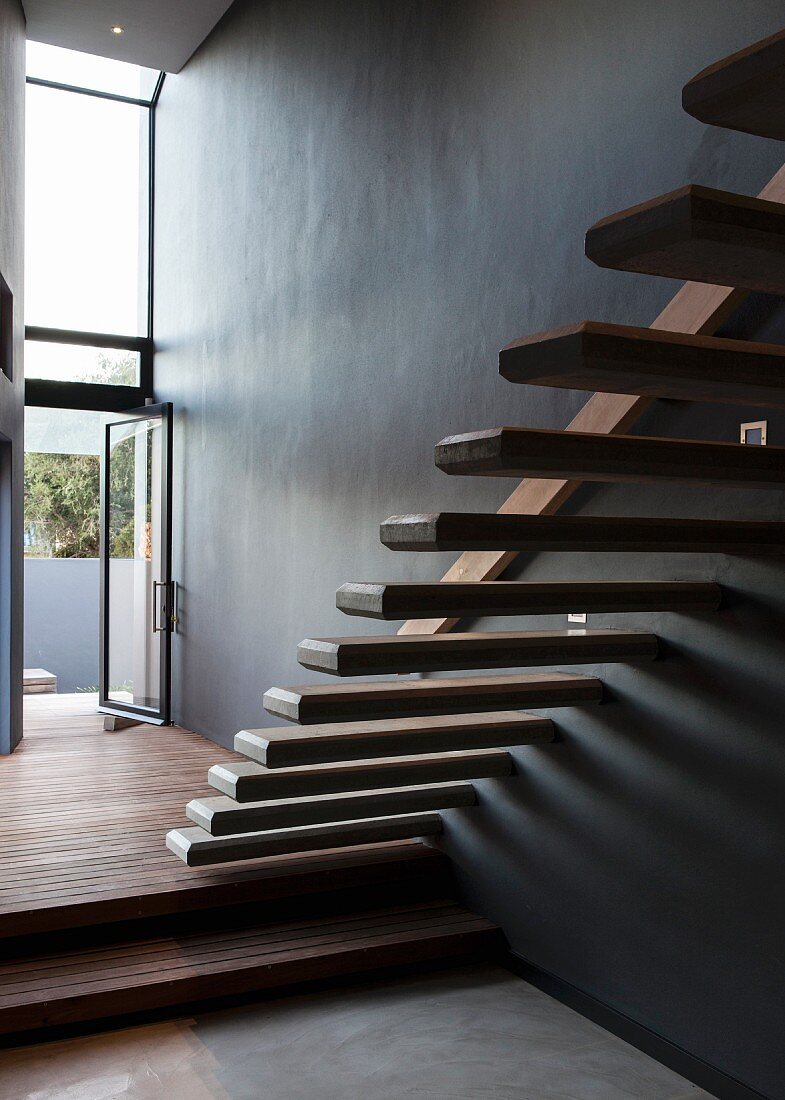 An der Wand befestigte frei auskragende Treppenstufen in minimalistischem Treppenraum mit offener Terrassentür