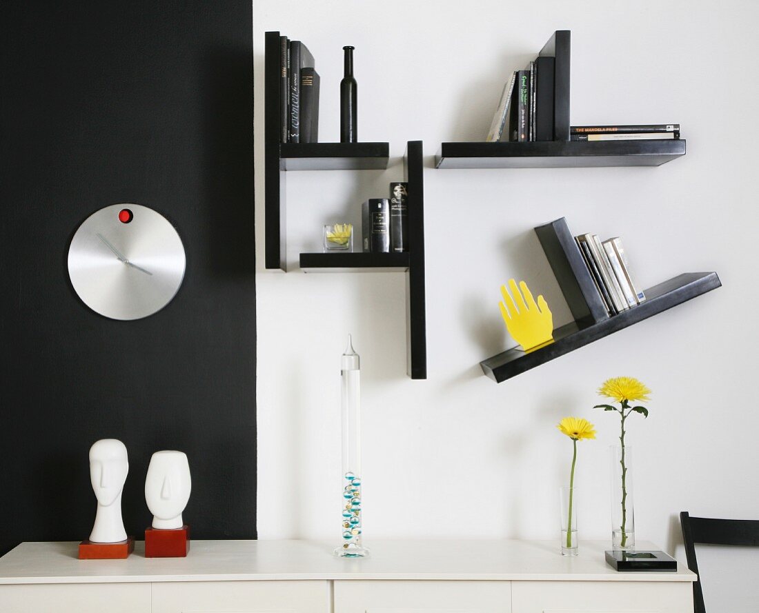 Sideboard against black and white wall with small shelves arranged asymmetrically