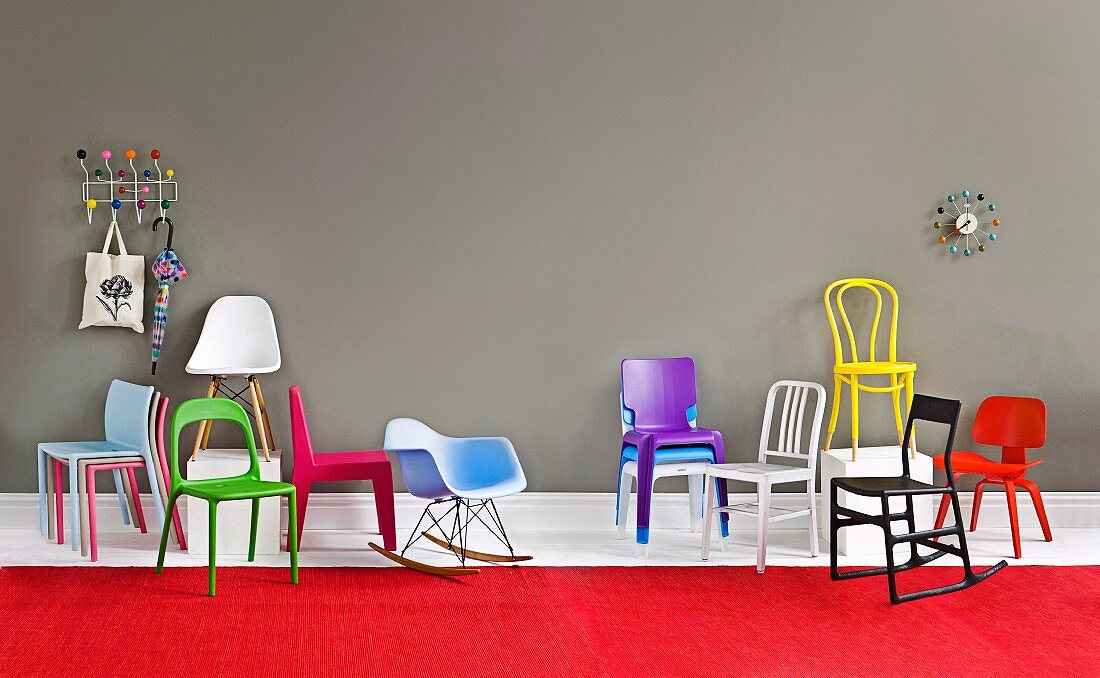 Various chairs of different colours, umbrella hanging from coat rack and wall clock