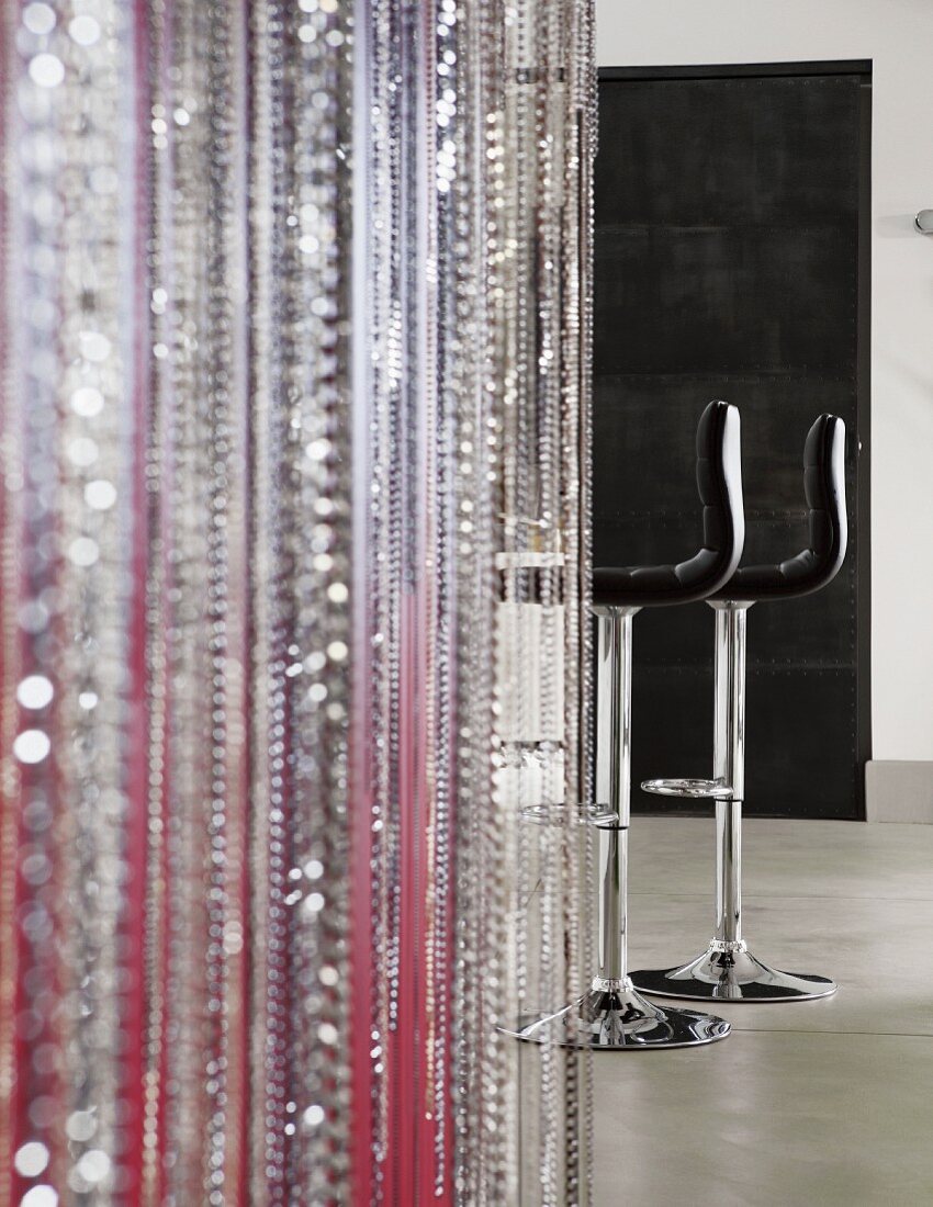 Bead curtain in various colours; black leather bar stools in background