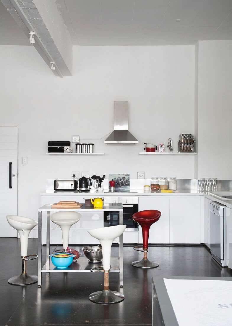 Designer Barhocker mit Schalensitz um thekenartigen Tisch in minimalistischer Küche