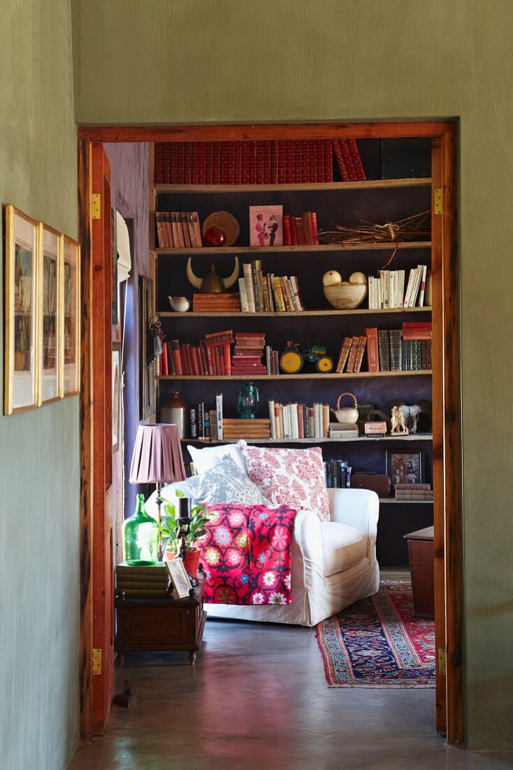 Green-painted foyer with open double doors and view of white armchair in front of bookcase