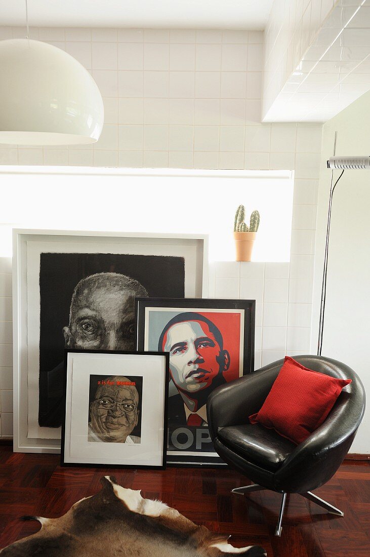 Black, leather swivel chair in front of collection of pictures and portrait of Obama leaning on wall