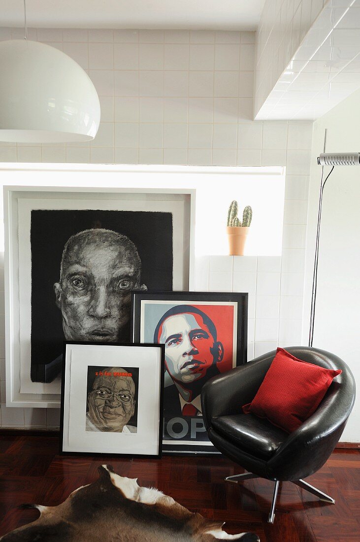 Schwarzer Lederdrehstuhl vor Bildersammlung und Obama- Portrait