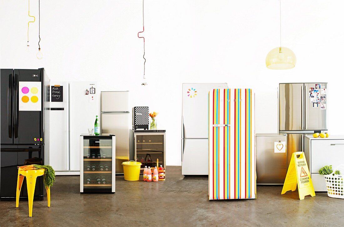 Various fashionable fridges, drinks and a yellow stool