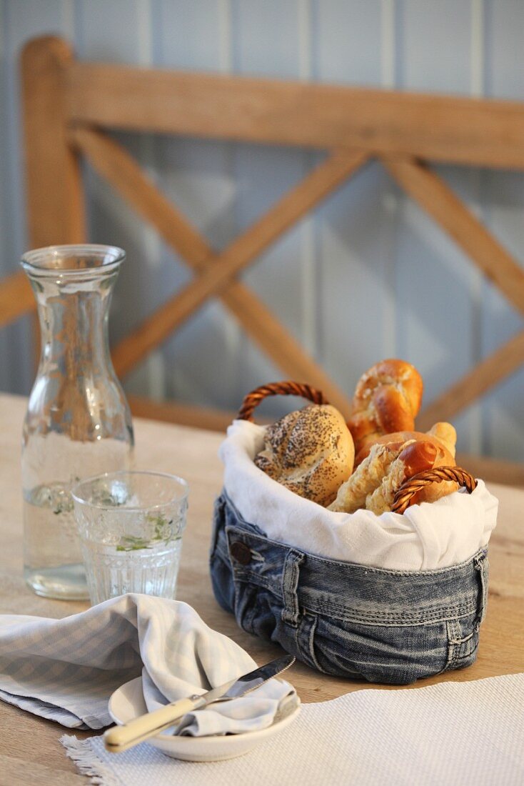 Frühstücksgebäck in selbstgefertigtem Brotkorb aus Jeansstoff auf Tisch in ländlichem Ambiente