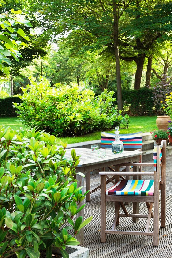 Director's chairs with colourful, striped fabric and table on deck in garden
