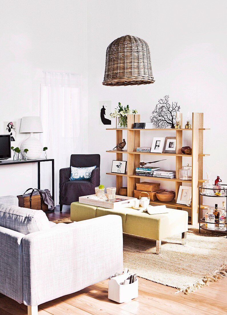 Modernes Wohnzimmer mit Sofa, Tisch, Teppich, Holzstellage mit Dekogegenständen und Korblampe