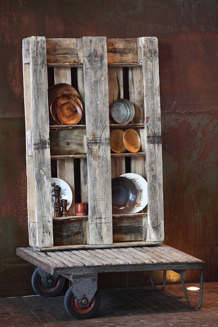 Holzpalette als offenes Regal mit Deko-Tellern auf Möbelhund vor Cortenstahl Wand