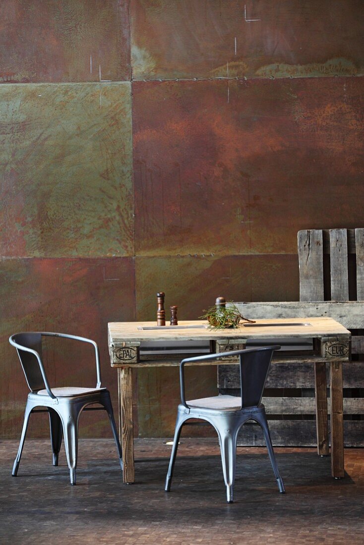 Rustikaler Esstisch aus Palette und Metallstühle vor Cortenstahl Wand