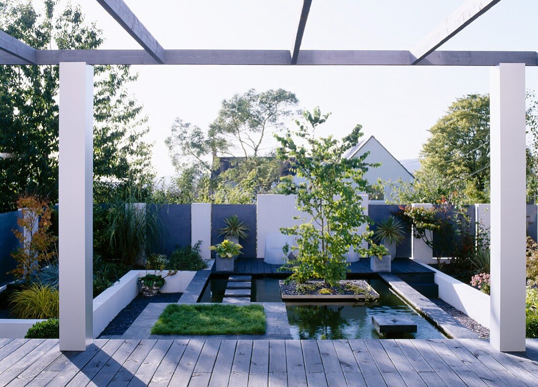 Terrasse mit Pergola vor gestyltem Garten mit Wasserbecken