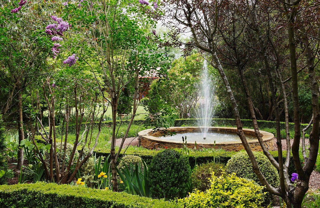 Fountain in round basin in landscaped gardens