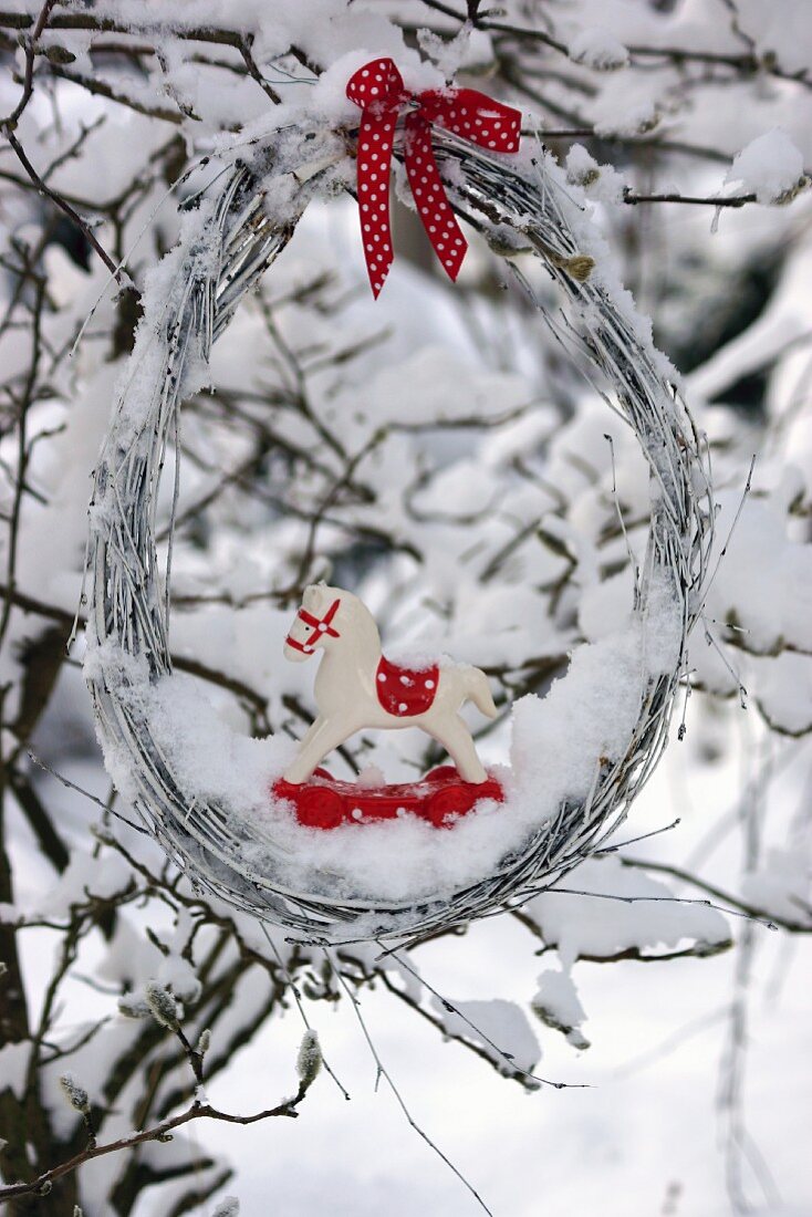 Willow wreath with wooden horse in snow