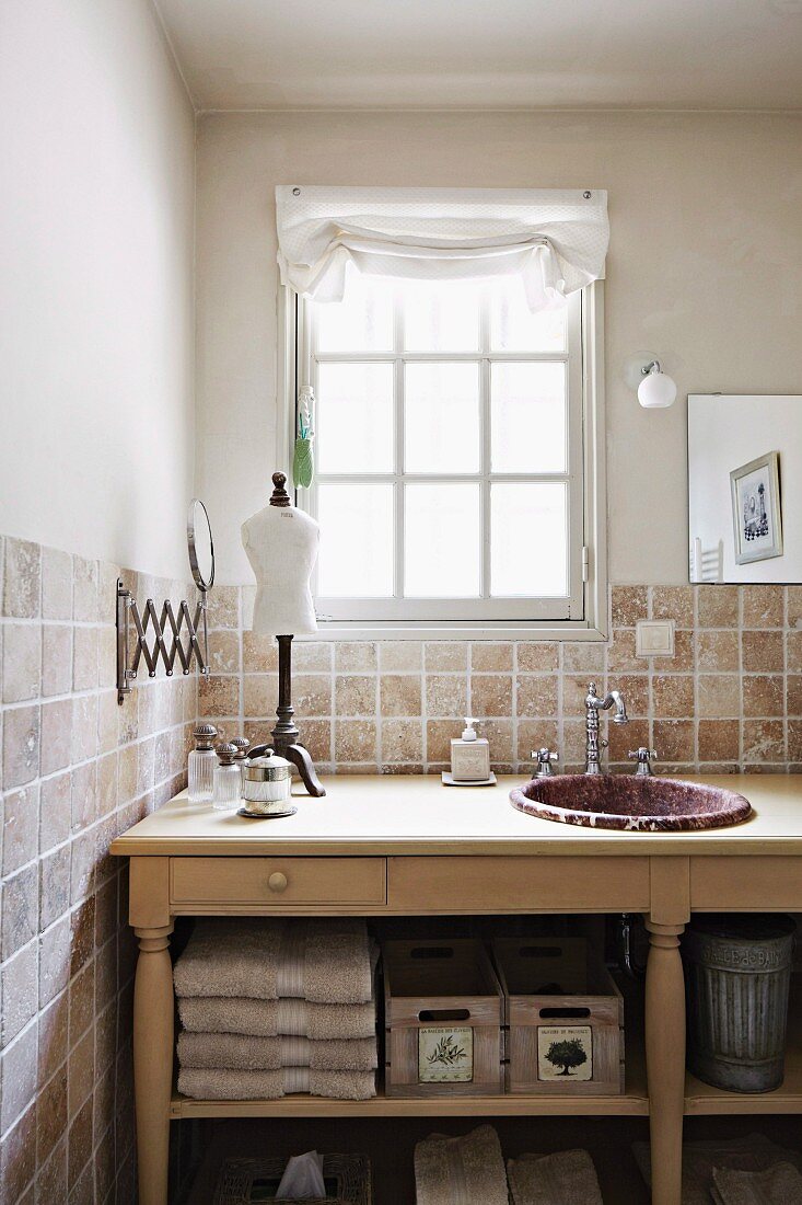 Ländlicher Waschtisch mit eingebautem Waschbecken vor gefliester Wand und Sprossenfenster in ländlichem Ambiente