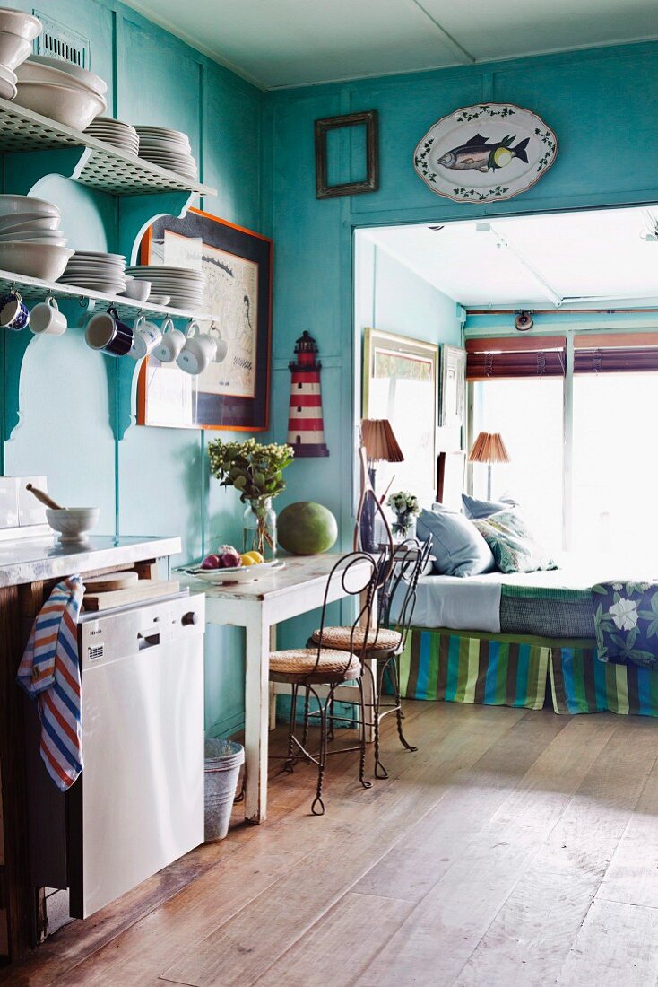 Türkisblau gestrichene Vintage-Küche mit Tagesbett in Fensternische und maritimer Wanddeko