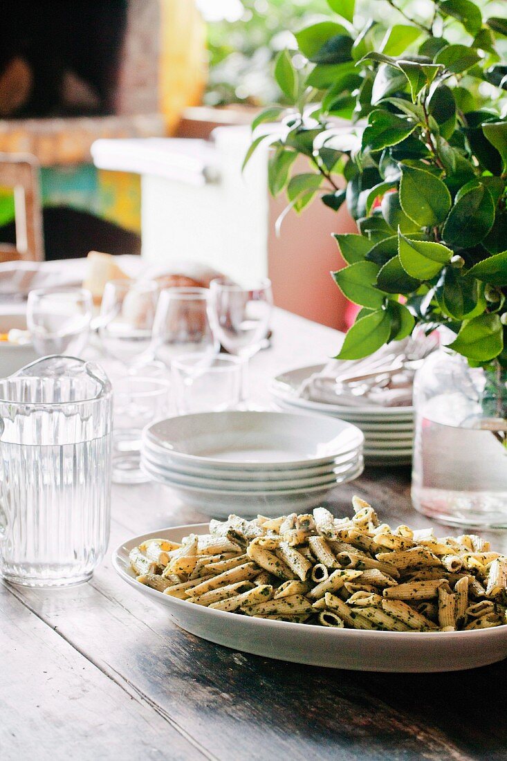 Stack of crockery and a dish of pasta on a table in a garden