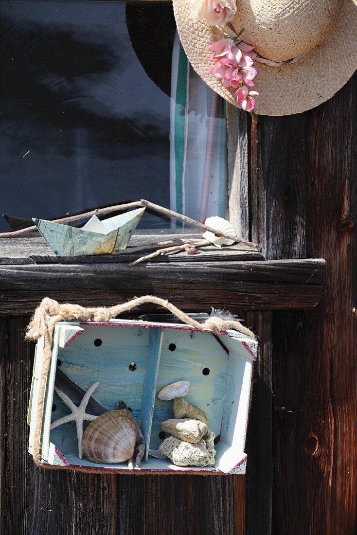 Stones, shells, driftwood and starfish in old, hand-painted fruit crate upcycled as display case