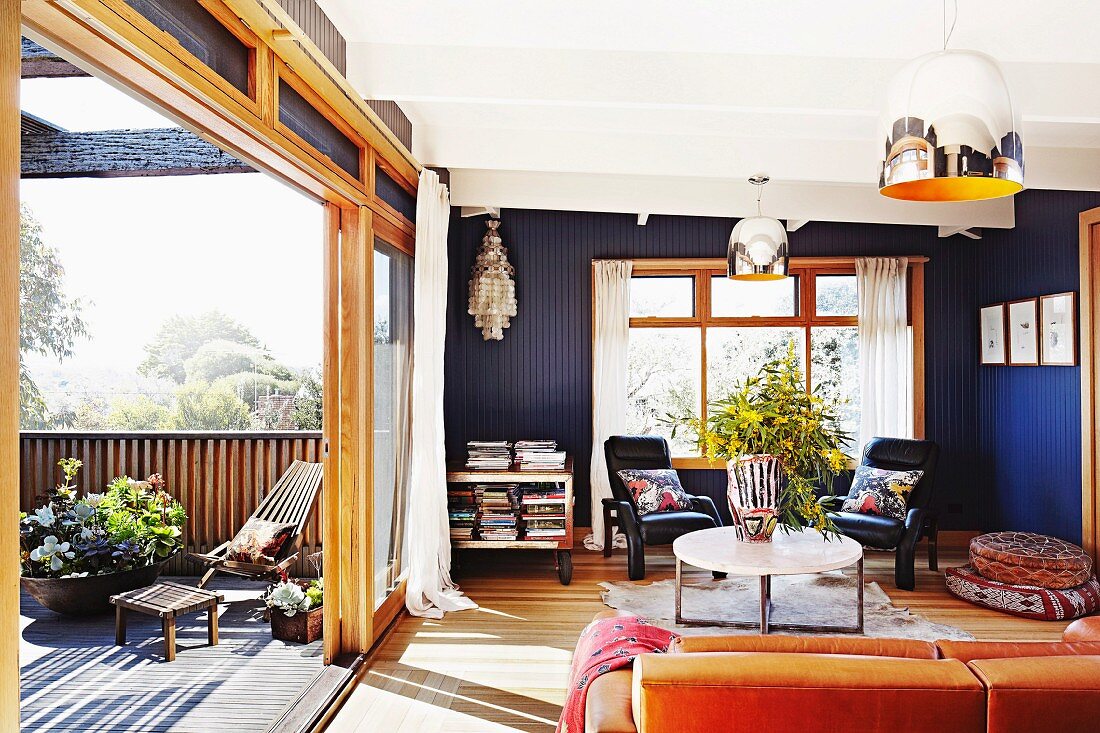 Blau getönter Wohnraum mit Couchtisch, teilweise sichtbarem Sofa & offener Schiebetür zur Terrasse