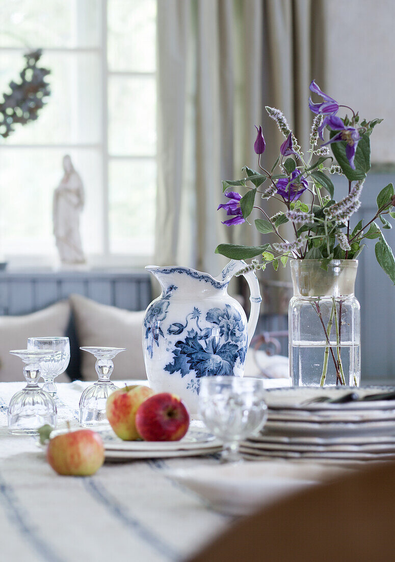 Stillleben mit Äpfeln, Geschirr und Blumenvase auf einem Esstisch