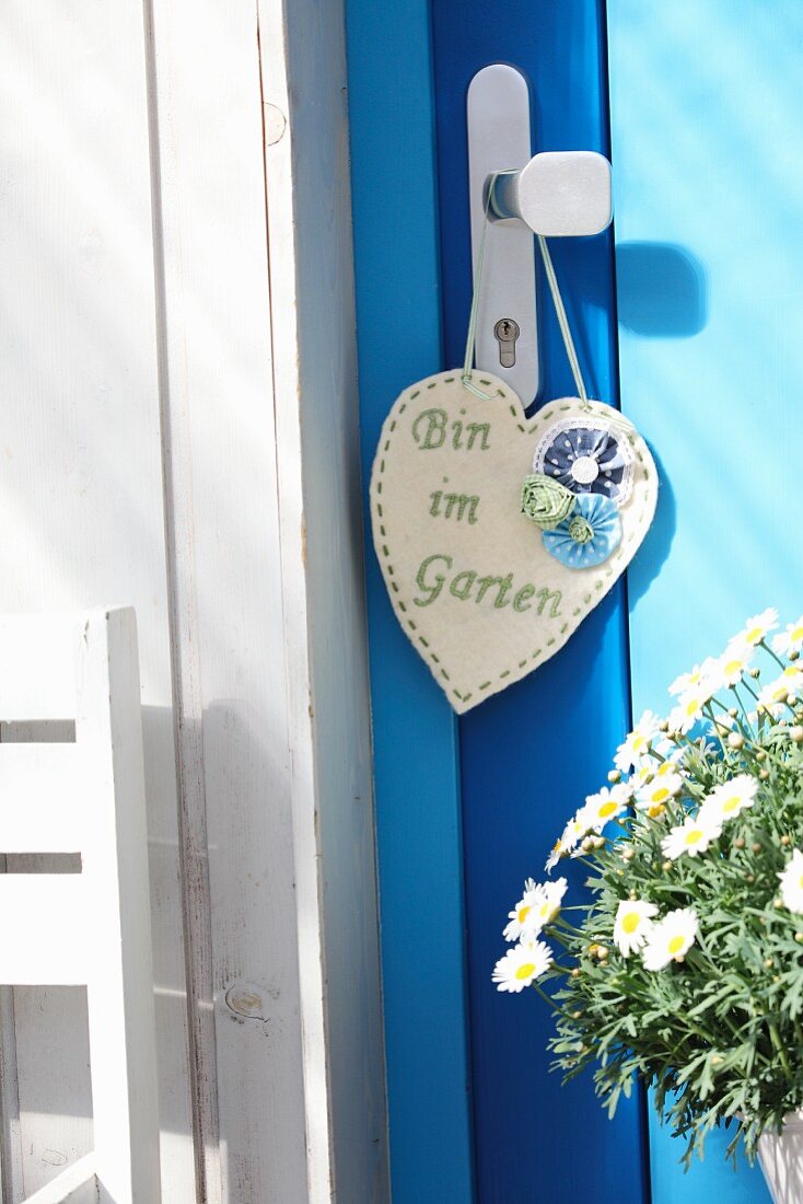 Hand-crafted, heart-shaped felt sign with embroidered message hanging from doorknob