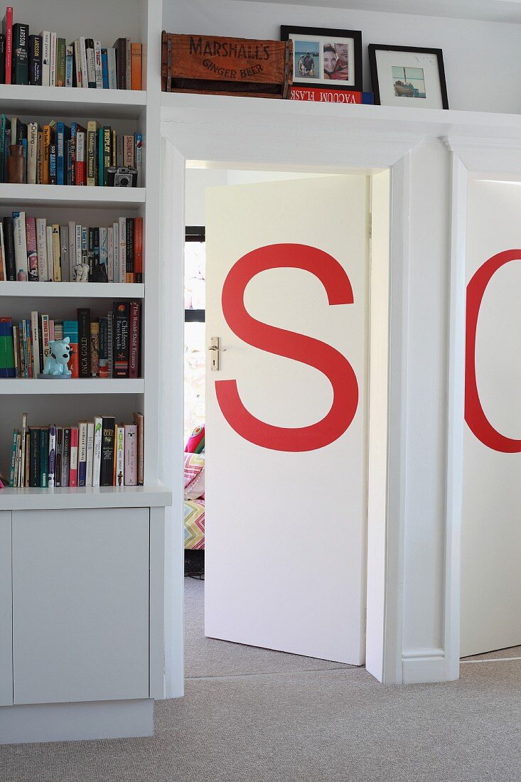 Von Einbauregalen umrahmte Zimmertüren, verziert mit roten Buchstaben