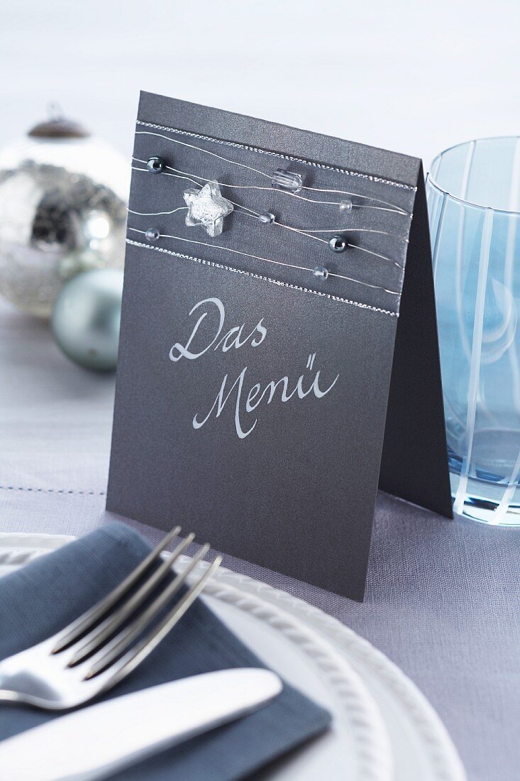 Menu made from folded cardboard decorated with ribbon and beads threaded on silver wire