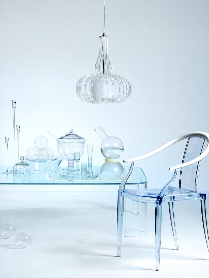 Nicht wirklich - Glasbehälter auf transparentem Tisch und Stuhl aus Acrylglas unter Hängeleuchte aus lamellenförmigem Schirm