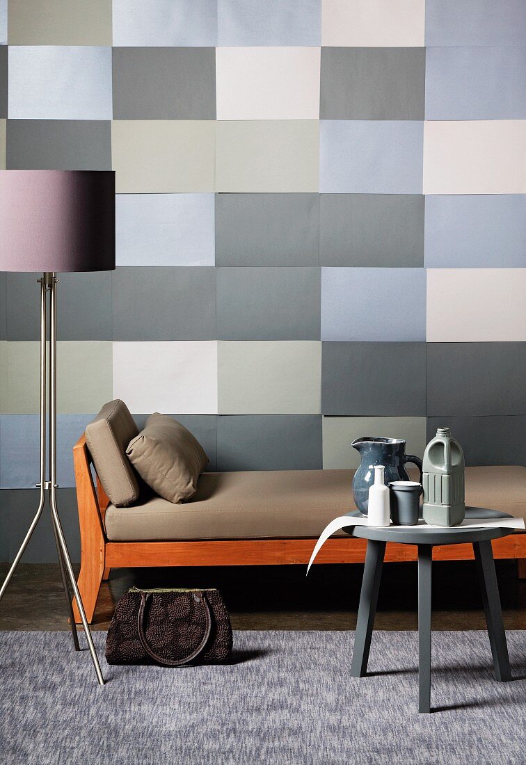 Graphic wall design of rectangles in shades of grey combined with colour-coordinated standard lamp, side table and couch