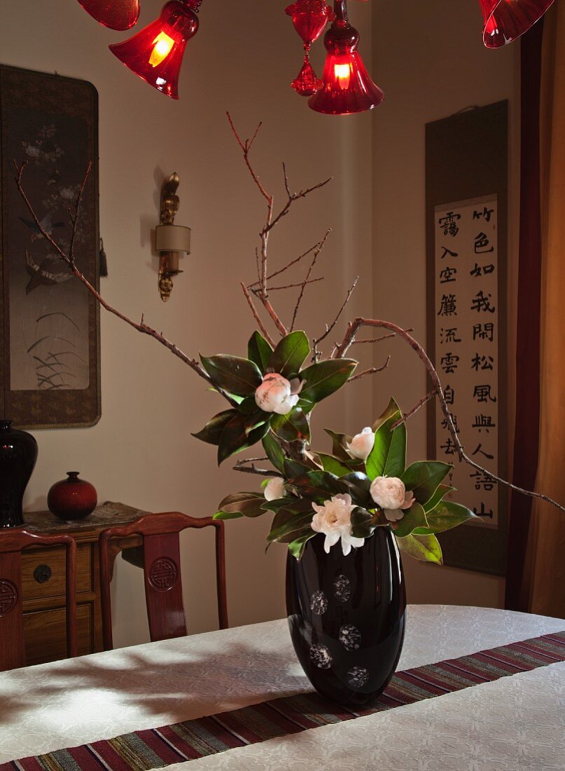 Asiatisch angehauchter Wohnbereich mit chinesischen Wandbehängen und einem Blumenarrangement in schwarzer Lackvase