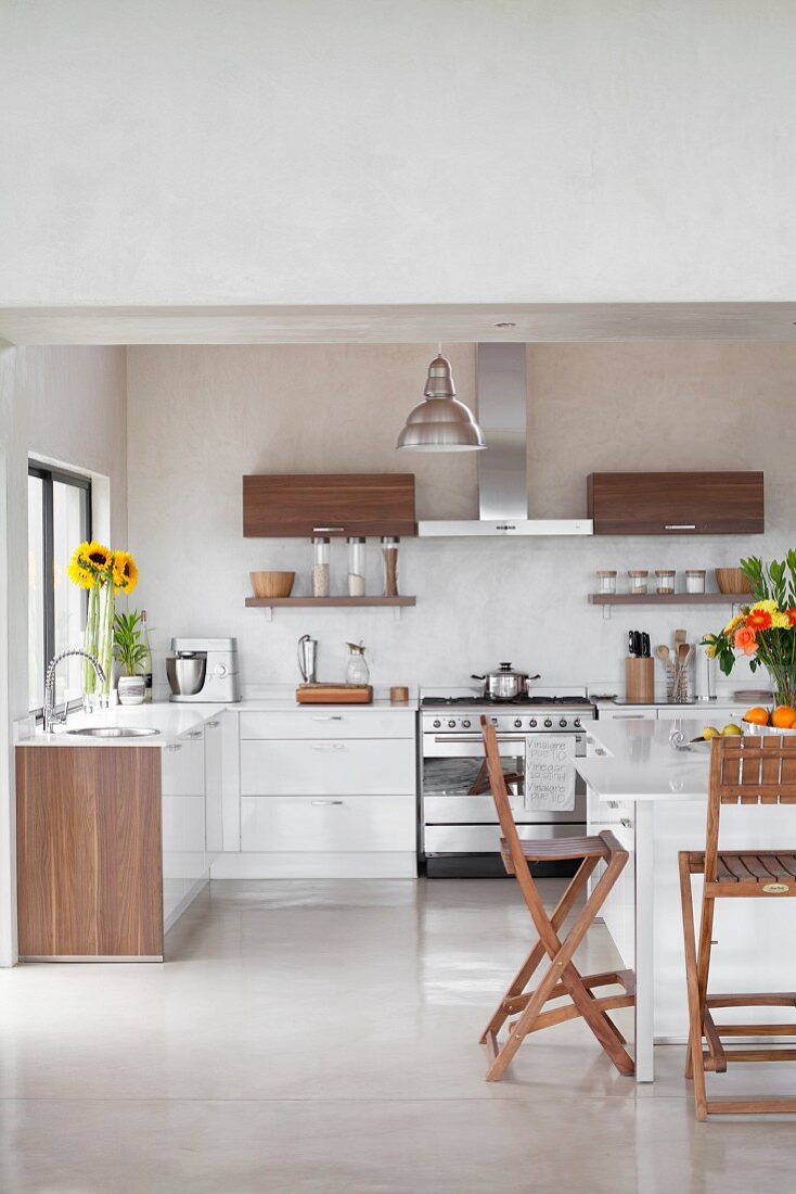 White fitted kitchen with wooden accents on doors and folding chairs at breakfast tables