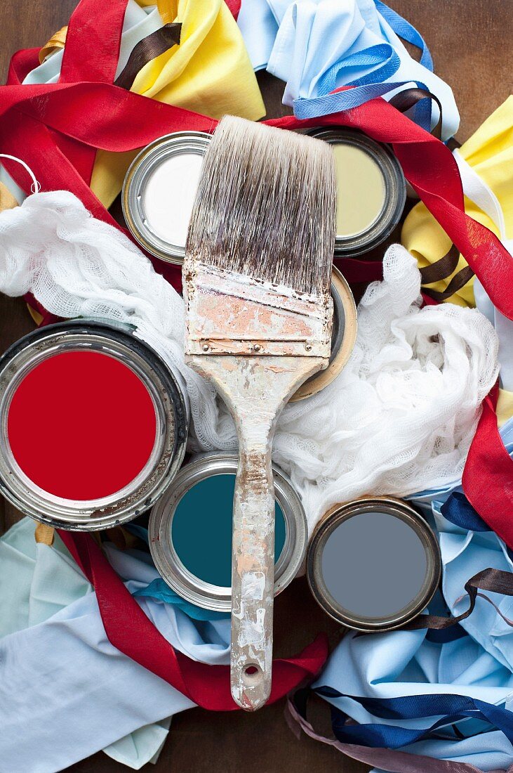 Still-life of paintbrushes, paint pots, fabrics & ribbons