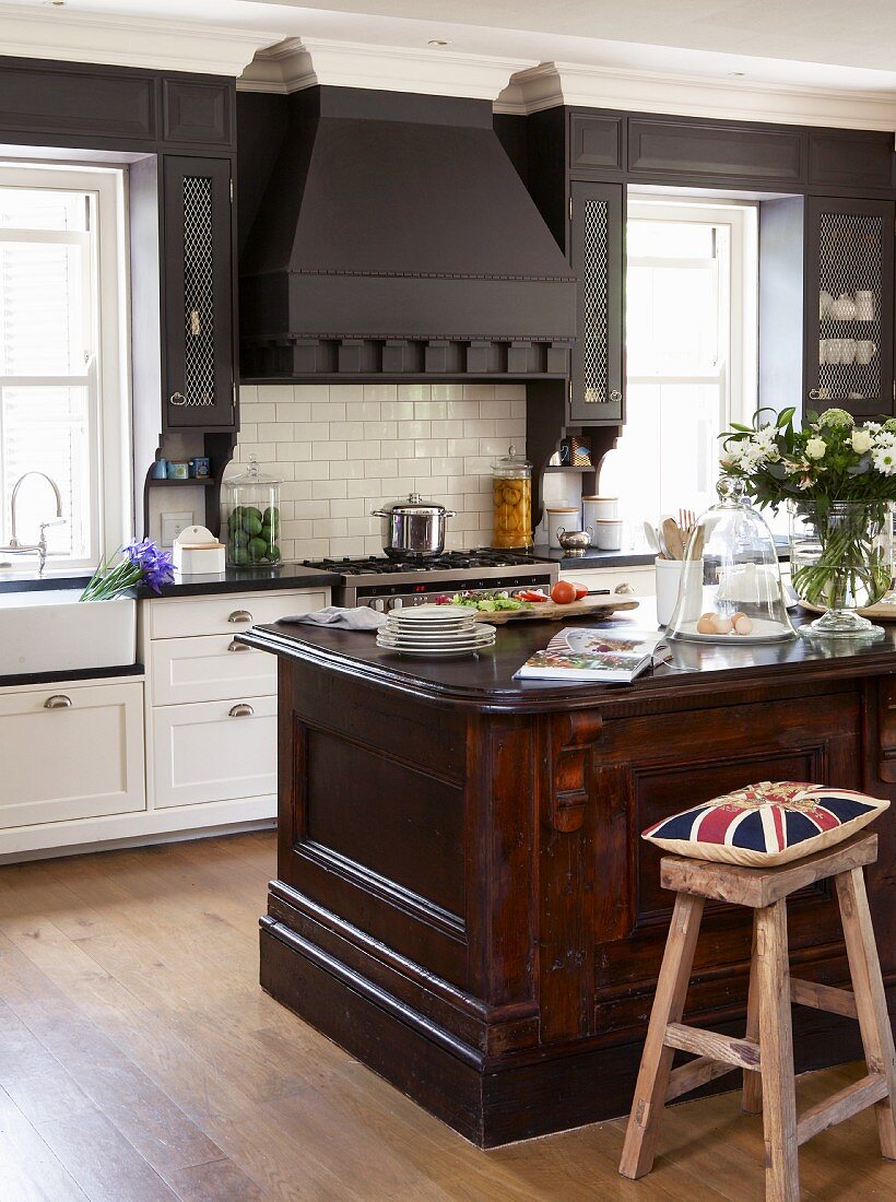 Union Flag cushion on bar stool at solid wood counter in open-plan, country-style kitchen