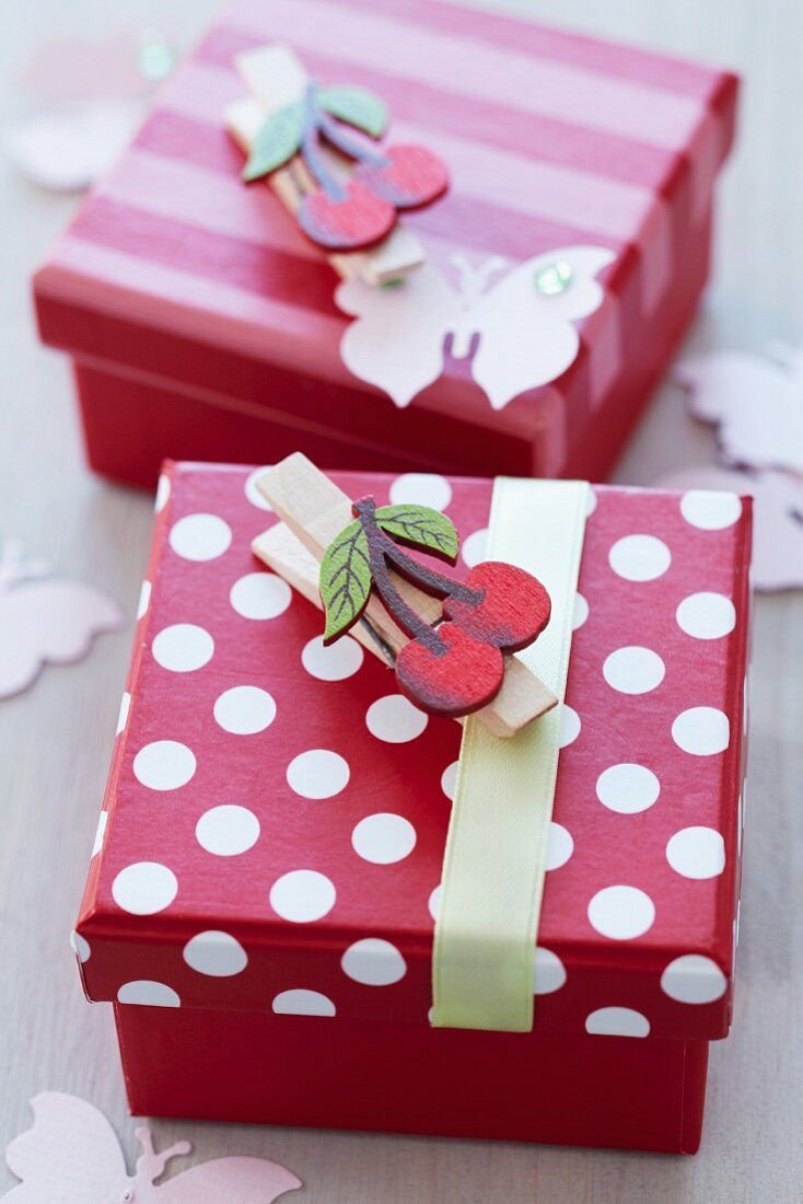 Pretty, red and white gift boxes decorated with clothes pegs with cherry motifs