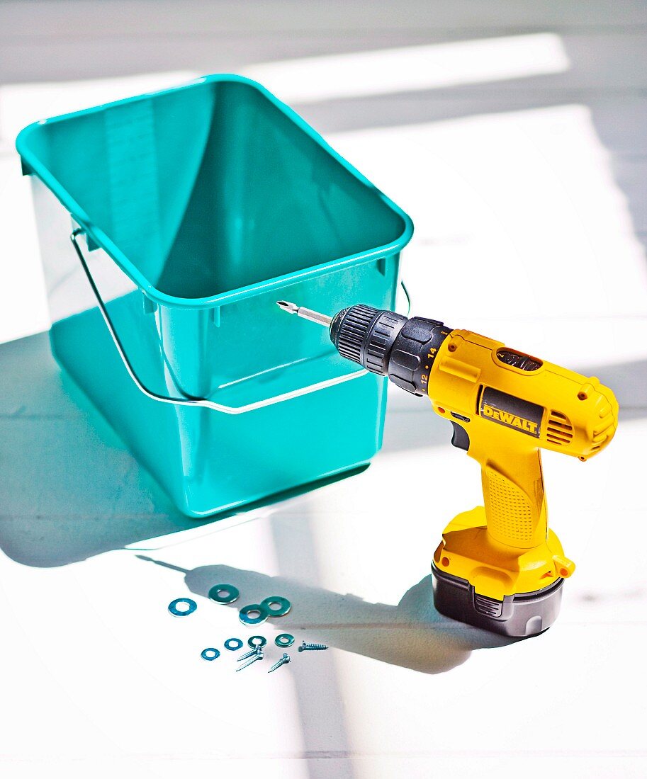 Yellow cordless drill-driver in front of mint green bucket