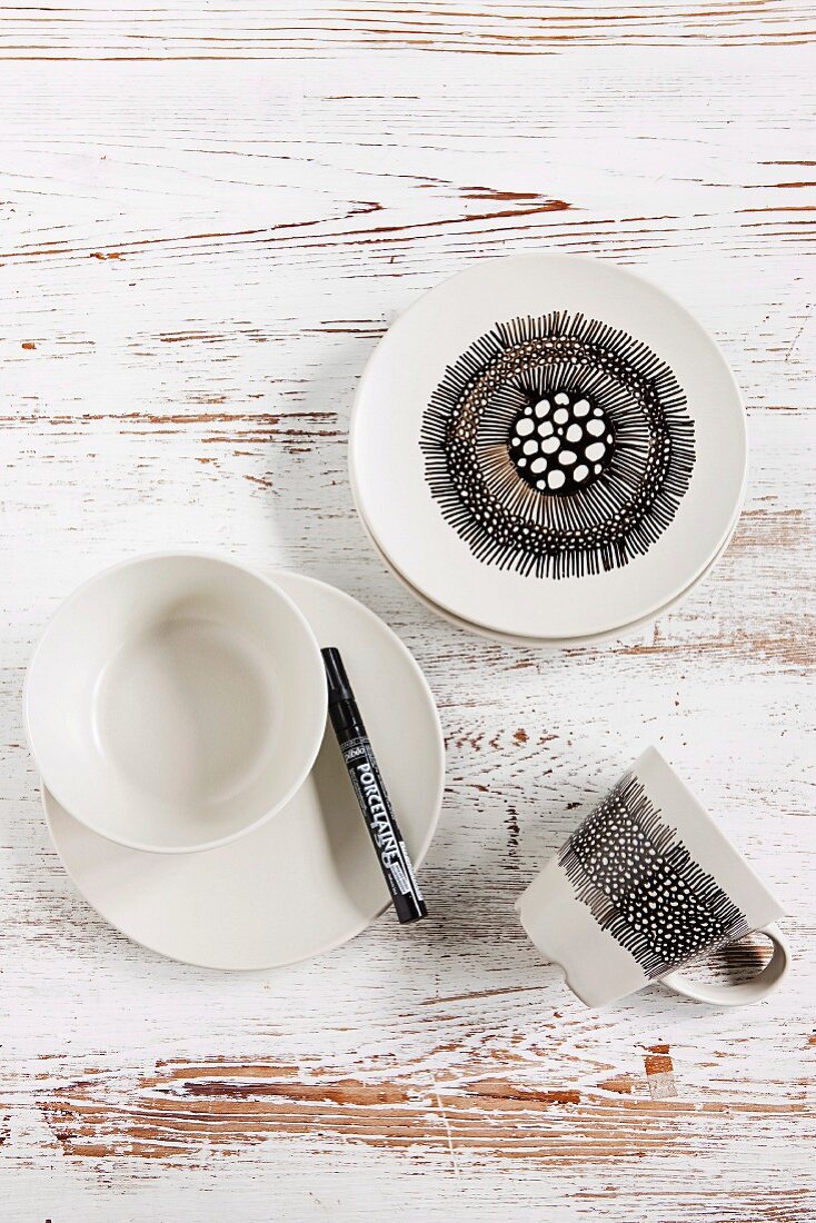 White crockery decorated with black ceramic marker on white, distressed wooden surface