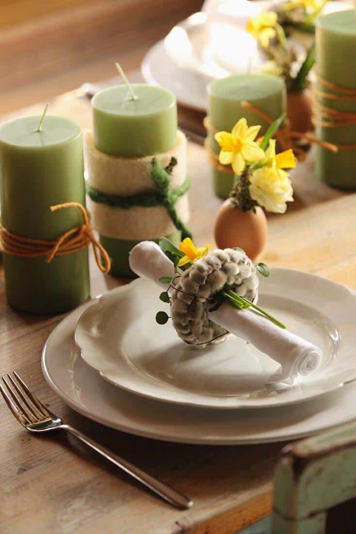 Pussy willow napkin ring on place setting with green candles and Easter arrangements on table