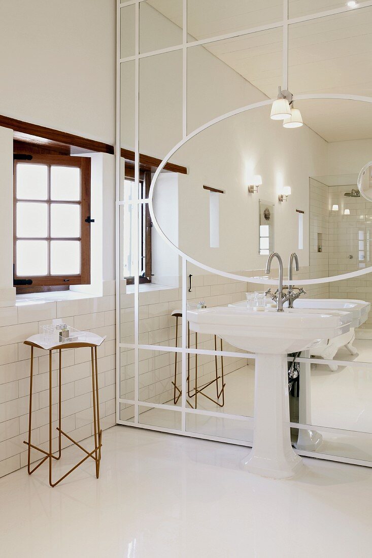 Spiegel mit aufgeklebten, weissen Holzleisten, davor Standwaschbecken, an der Seite filigraner Metall Beistelltisch unter Sprossenfenster
