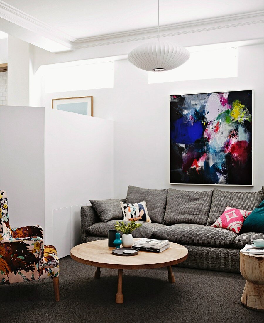 Lounge area with designer furniture and brightly coloured artwork on wall next to white partition