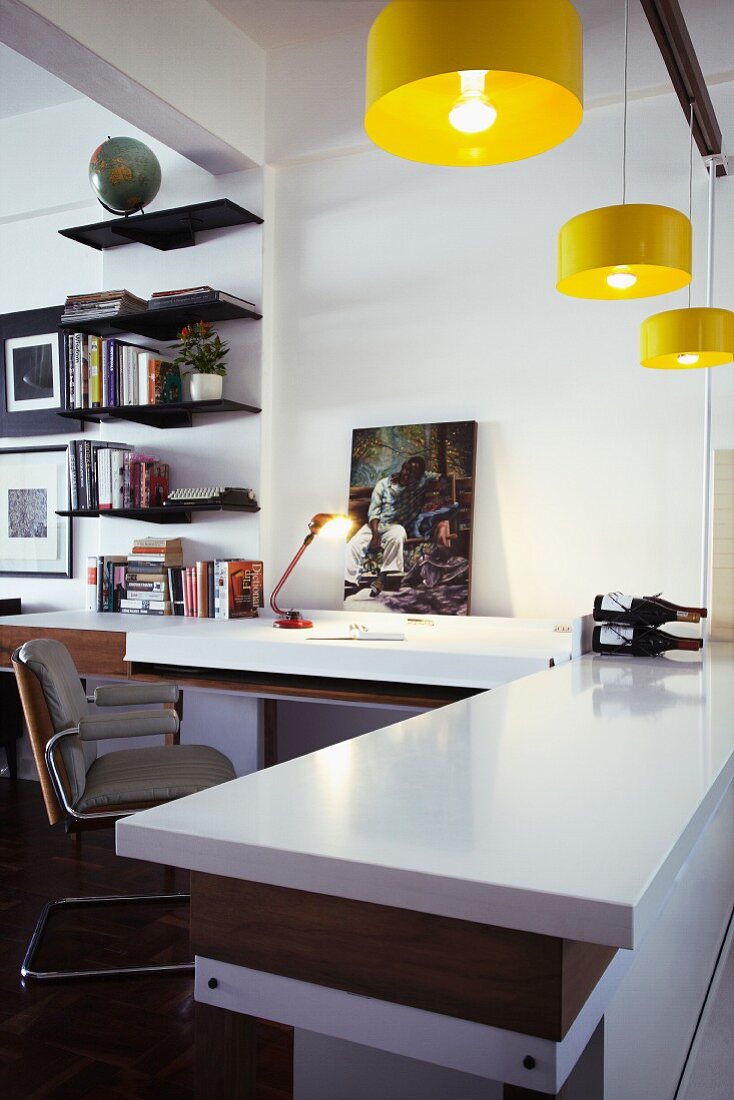 Offener Wohnraum mit Schreibtisch und angrenzender Küchentheke unter gelben Hängelampen