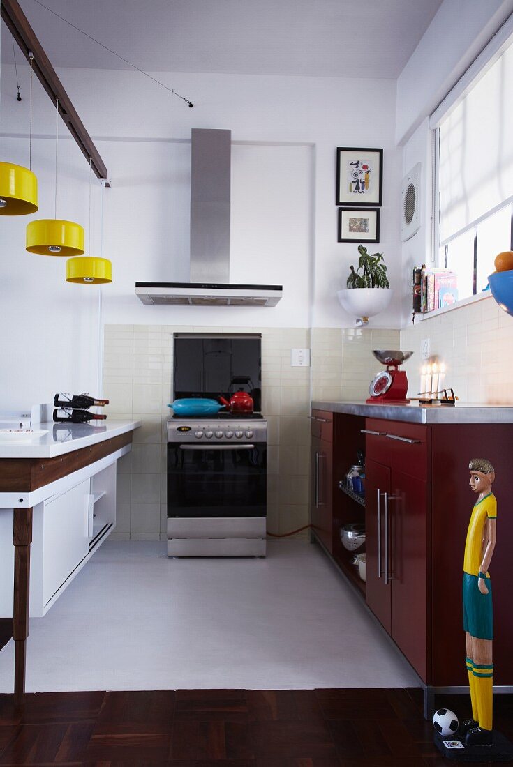 Kitchen with yellow pendant lamps above counter and free-standing cooker below extractor hood