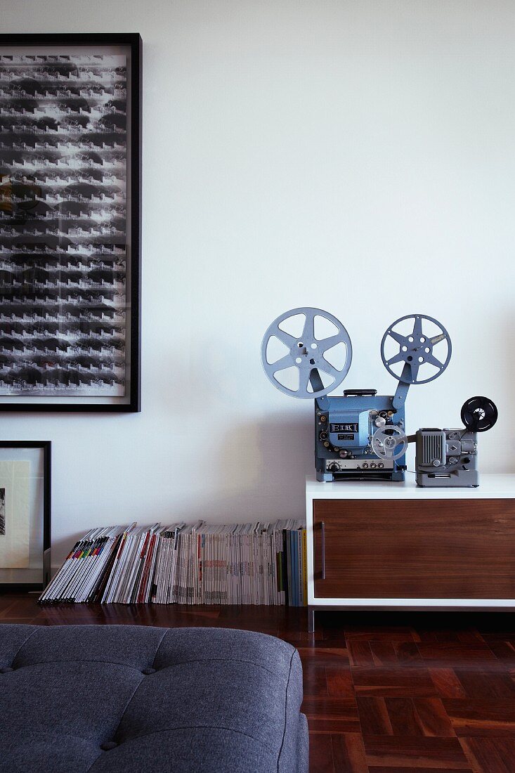 Old film projector decorating sideboard and modern artwork on wall
