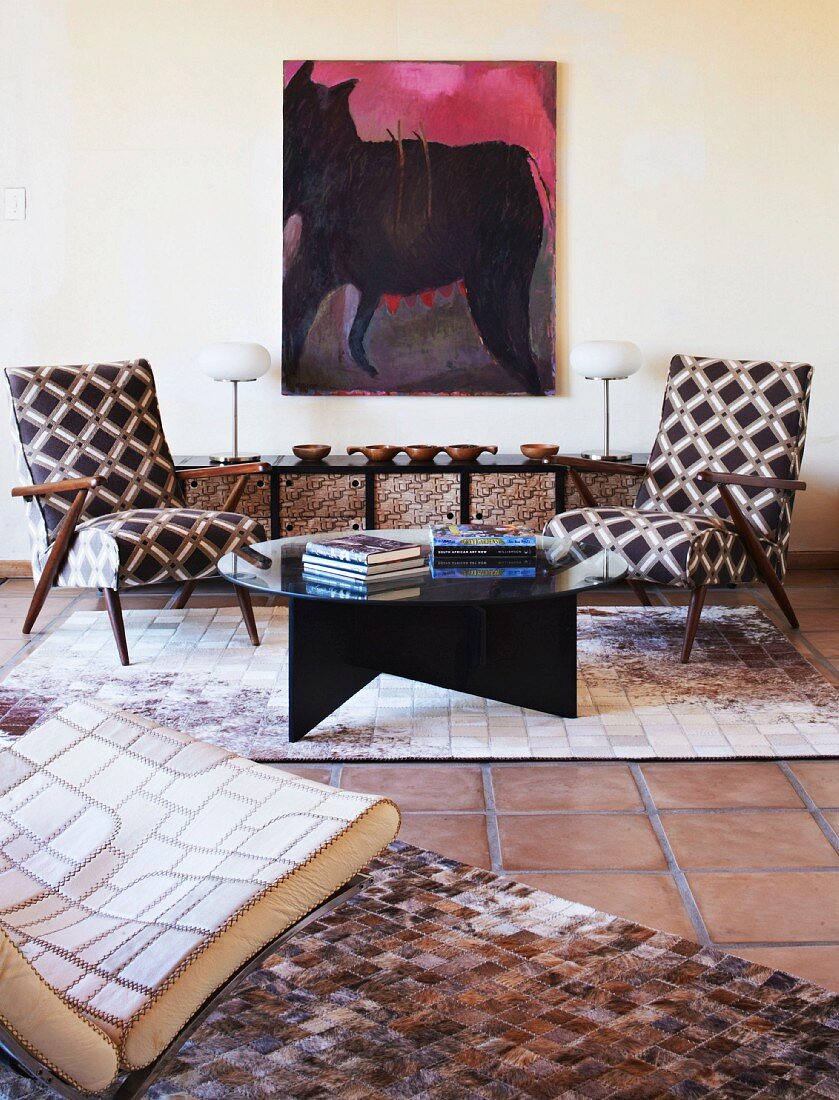 Zwei geometrisch gemusterte Retrosessel vor modernem Pferde-Gemälde; Sessel links im Vordergrund und Teppiche aus handgefertigtem Leder-Patchwork