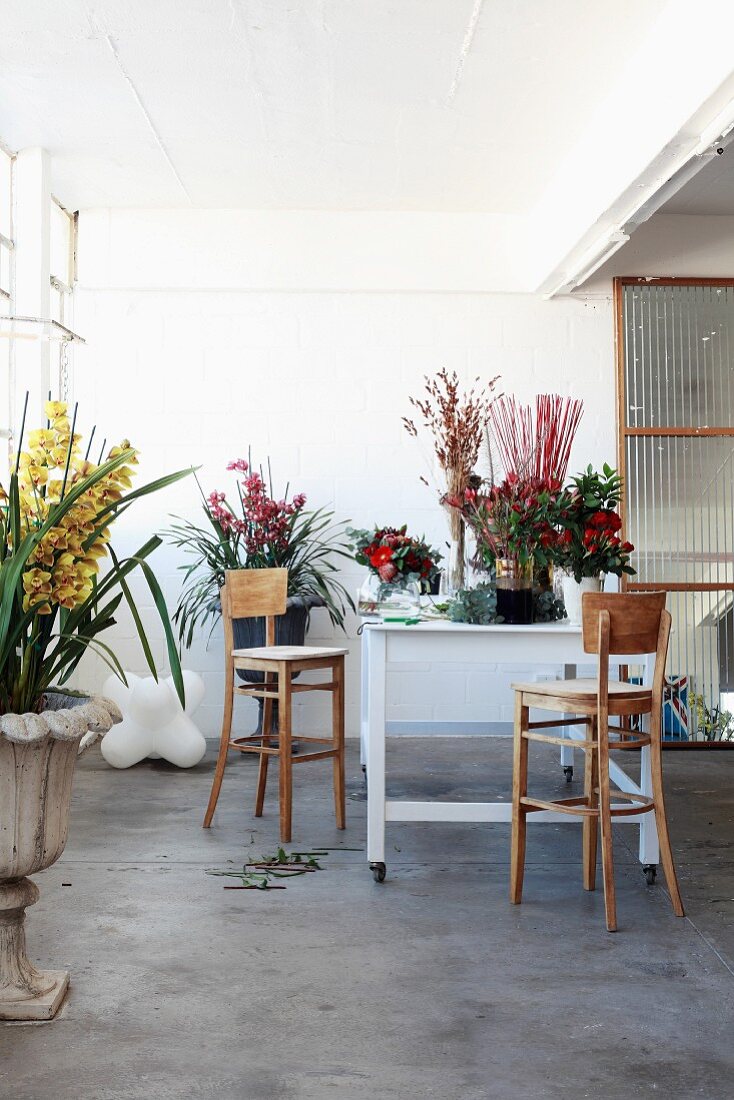 Arbeitstisch eines Floristen umgeben von verschiedenen Blumen in schlichtem Raum