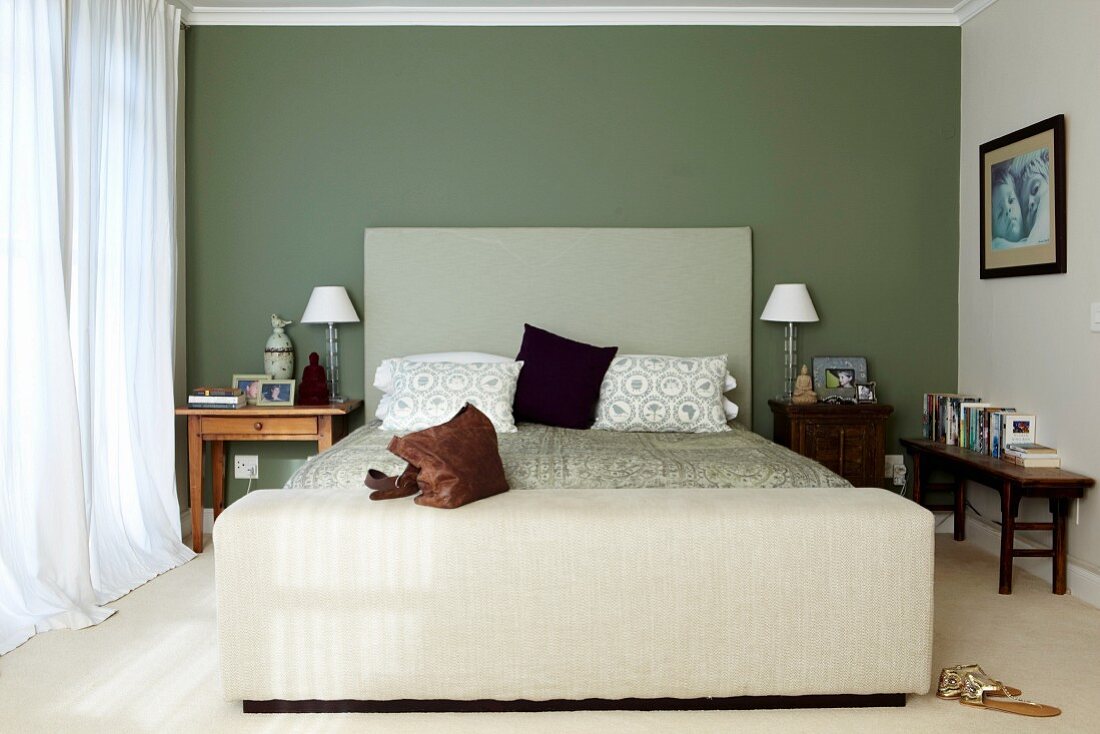 Schlichtes Bett mit Kopfteil an grün getönter Wand in klassischem Schlafzimmer