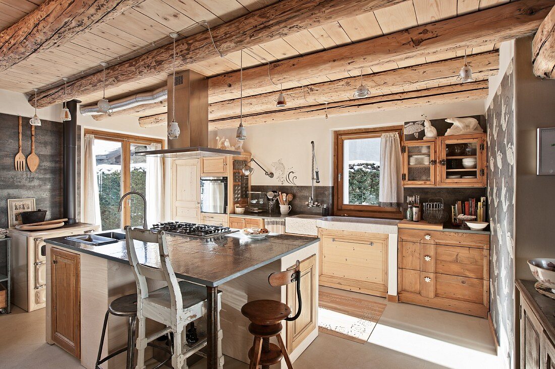 Mittelblock mit Vintage Küchenstühlen in rustikaler Einbauküche einer Holzhütte